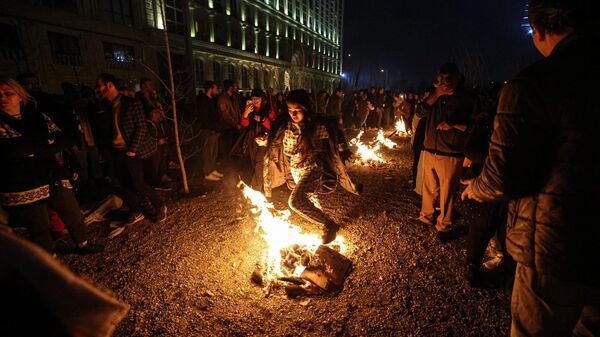 Женщина прыгает через костер накануне праздника Огня или Чахаршанбе Сури в Иране. 12 марта 2024
