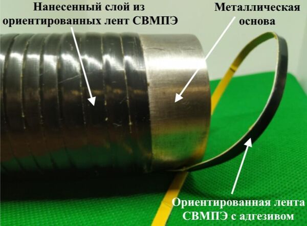 Фото ориентированной ленты сверхвысокомолекулярного полиэтилена с адгезивом на металлическом цилиндре. Пример формирования цапфы подшипника скольжения.