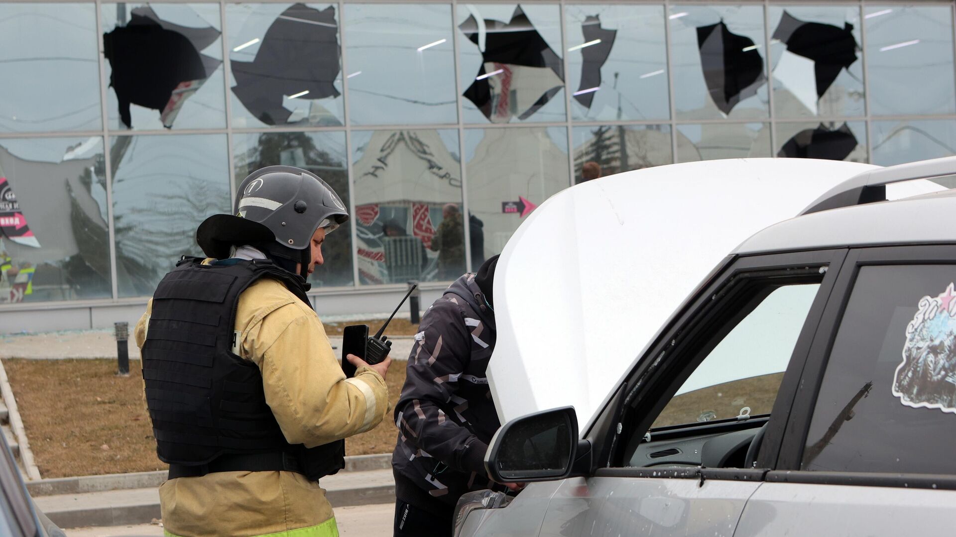 Сотрудник противопожарной службы осматривает автомобиль, поврежденный в результате атаки беспилотного летательного аппарата в Белгороде - РИА Новости, 1920, 14.03.2024