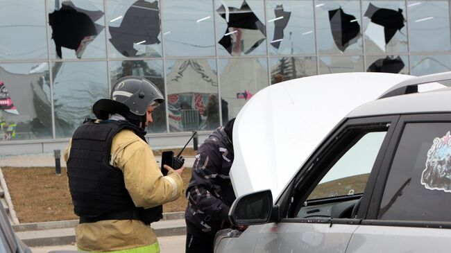 Сотрудник противопожарной службы осматривает автомобиль, поврежденный в результате атаки беспилотного летательного аппарата в Белгороде