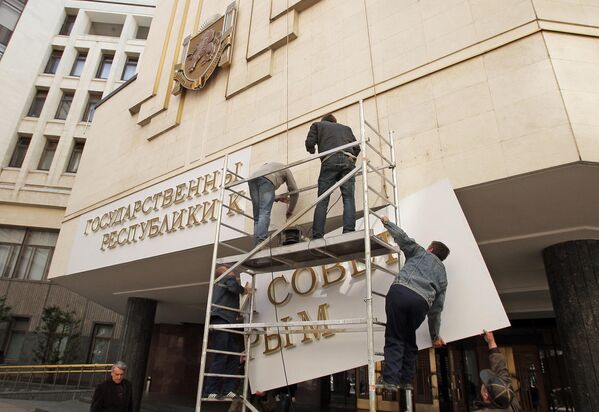 Рабочие устанавливают новую вывеску на здание парламента республики Крым