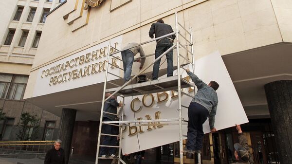 Рабочие устанавливают новую вывеску на здание парламента республики Крым