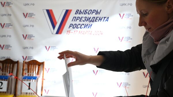 Женщина голосует на выборах президента России на избирательном участке