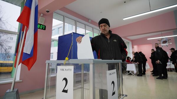 Мужчина голосует на выборах президента России на избирательном участке №733 памяти Героя России Александра Боброва в Мариуполе