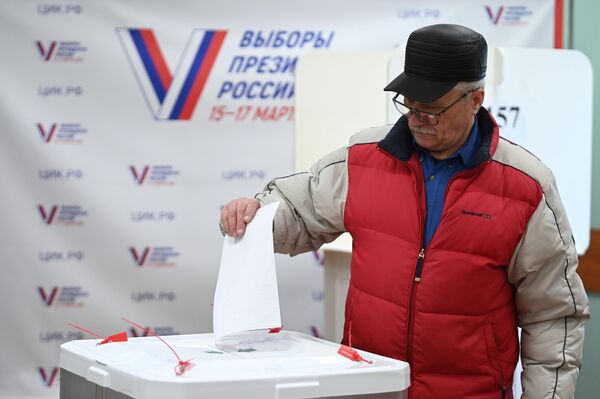 Мужчина голосует на выборах президента России на избирательном участке в Москве