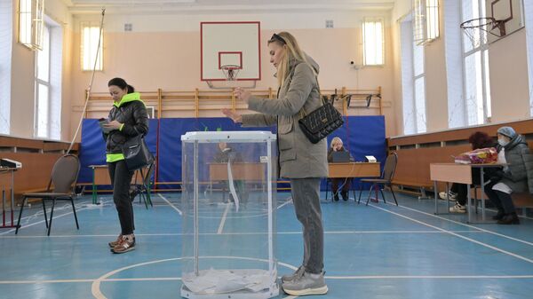 Девушка голосует на выборах президента России на избирательном участке №2149 в Москве