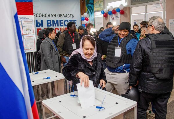 Женщина голосует на выборах президента РФ в присутствии иностранных наблюдателей на избирательном участке в Геническе