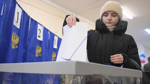 Девушка голосует на выборах президента России на одном из избирательных участков в Новосибирске