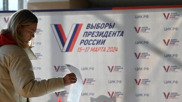 Женщина голосует на выборах президента России на избирательном участке в Москве