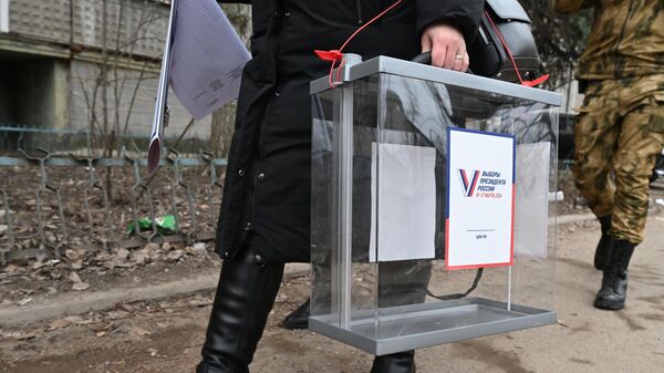 Член избирательной комиссии несет урну для выездного голосования в ходе выборов президента России в Луганске