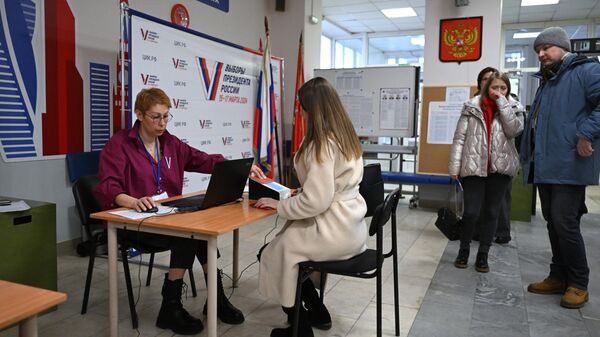 Люди голосуют на выборах президента России на избирательном участке в Москве
