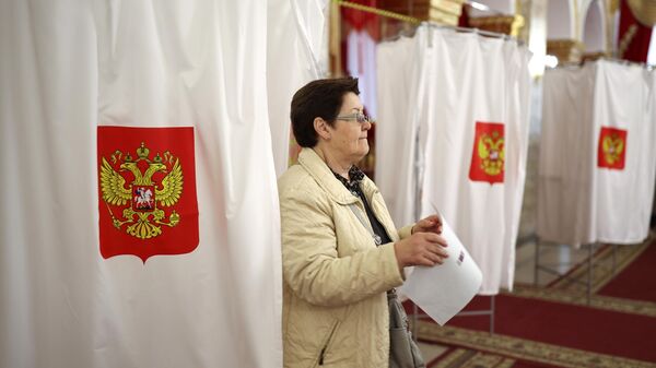 Женщина принимает участие в голосовании на выборах президента России