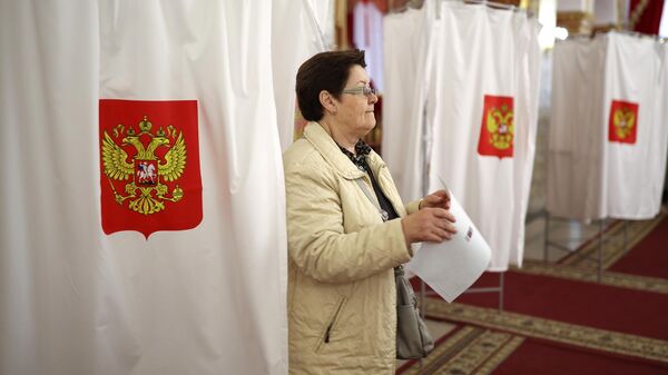 Женщина принимает участие в голосовании на выборах президента России