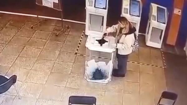Кадр видео с избирательного участка в Москве, где девушка вылила красящее вещество в урну с бюллетенями