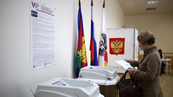 Женщина принимает участие в голосовании на выборах президента России на избирательном участке