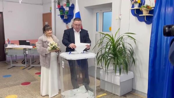 Жители города Тобольска Тюменской области Виктория и Рамиль голосуют на выборах президента РФ после церемонии бракосочетания в ЗАГС