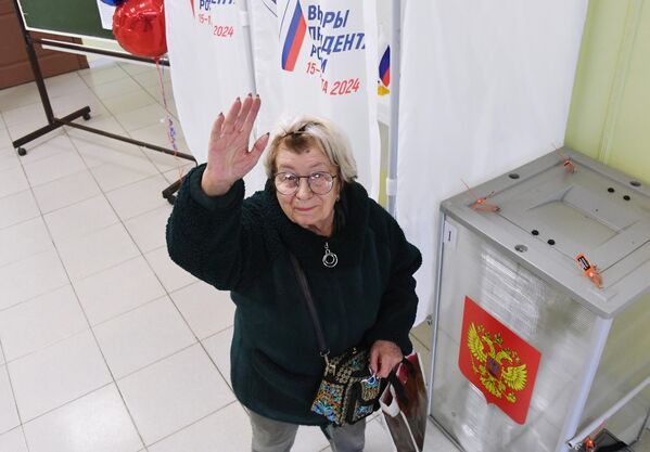 Женщина голосует на выборах президента России на избирательном участке №4126 во Владивостоке