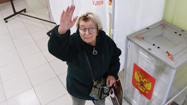 Женщина голосует на выборах президента России на избирательном участке №4126 во Владивостоке