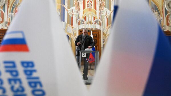 Мужчина голосует на выборах президента России на избирательном участке в Луганске