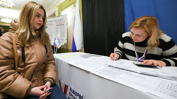 Девушка голосует на выборах президента России на избирательном участке в Донецке