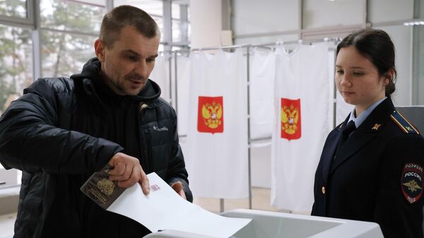 Мужчина голосует на выборах президента России на одном из избирательных участков в Симферополе