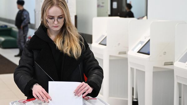 Девушка голосует на выборах президента России на избирательном участке
