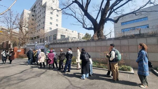 Люди стоят в очереди на избирательный участок в российском посольстве в Сеуле для голосования на выборах президента России