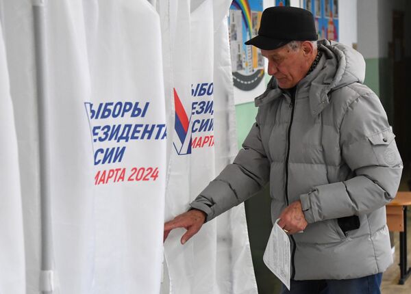 Мужчина голосует на выборах президента России на избирательном участке во Владивостоке
