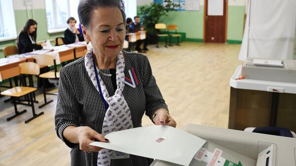 Женщина голосует на выборах президента России на избирательном участке во Владивостоке