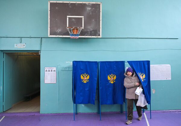 Женщина голосует на выборах президента России на избирательном участке в Новосибирске