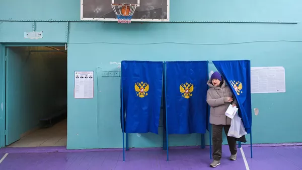 Женщина голосует на выборах президента России на избирательном участке в Новосибирске Женщина голосует на выборах президента России на избирательном участке в Новосибирске
