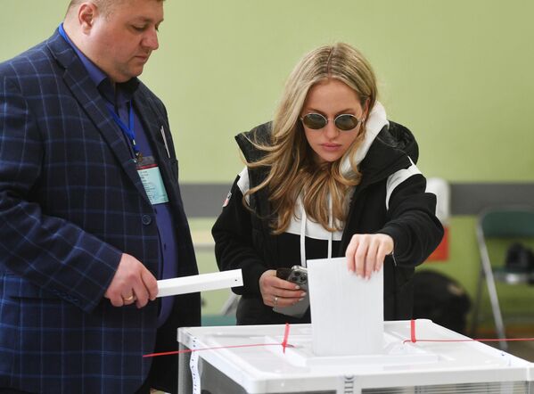 Девушка голосует на выборах президента России на избирательном участке в Москве