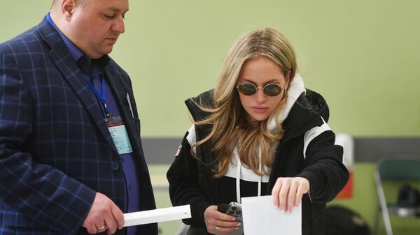 Девушка голосует на выборах президента России на избирательном участке в Москве
