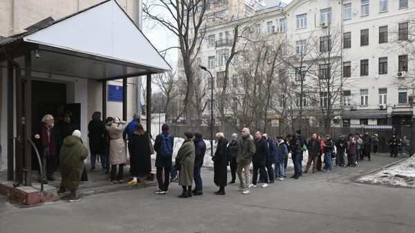 Люди стоят в очереди, чтобы проголосовать на выборах президента России на избирательном участке школы №2123 в Москве