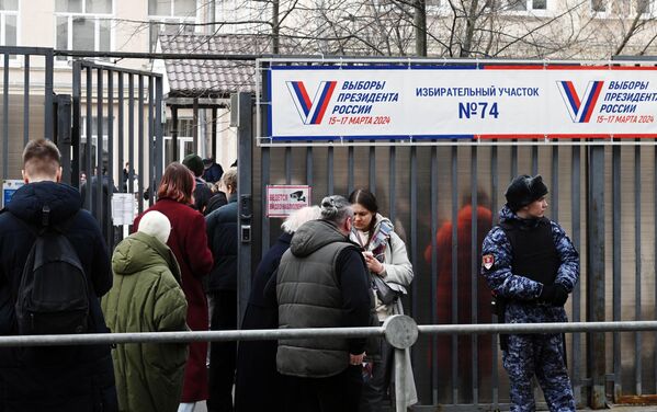 Люди стоят в очереди, чтобы проголосовать на выборах президента России на избирательном участке в Москве