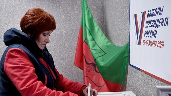 Женщина голосует на выборах президента России на избирательном участке в Мелитополе Запорожской области