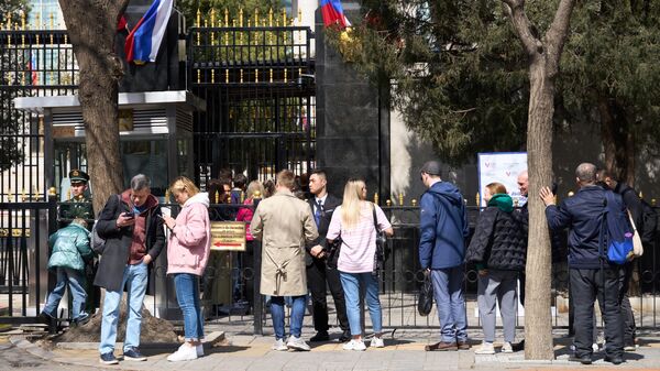 Люди стоят в очереди на избирательный участок в российское посольство в Пекине для голосования на выборах президента России