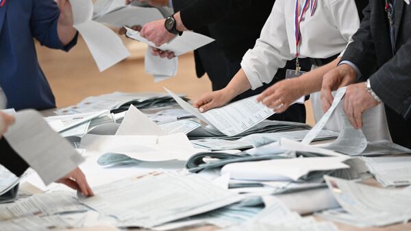Члены участковой избирательной комиссии подсчитывают голоса после окончания процедуры голосования на выборах президента России на избирательном участке  
