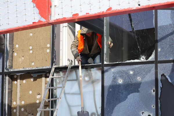Рабочий убирает осколки разбитых окон здания многофункционального спортивно-развлекательного комплекса Белгород-Арена, частично разрушенного в результате обстрела ВСУ в Белгороде