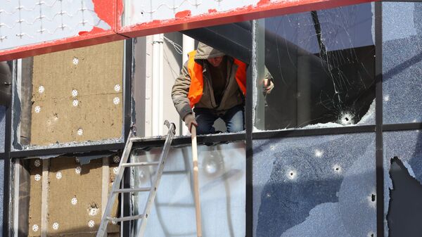 Рабочий убирает осколки разбитых окон здания многофункционального спортивно-развлекательного комплекса Белгород-Арена, частично разрушенного в результате обстрела ВСУ в Белгороде