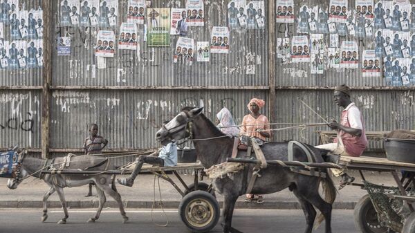 Местные жители проезжают мимо предвыборных плакатов в Даре, Сенегал 
