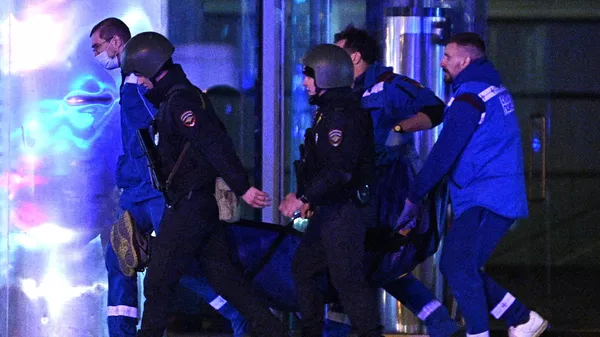 Οι αστυνομικοί και οι ιατρικοί υπάλληλοι μεταφέρουν έναν τραυματία έξω από την αίθουσα συναυλιών Crocus City Hall, όπου σημειώθηκαν οι πυροβολισμοί