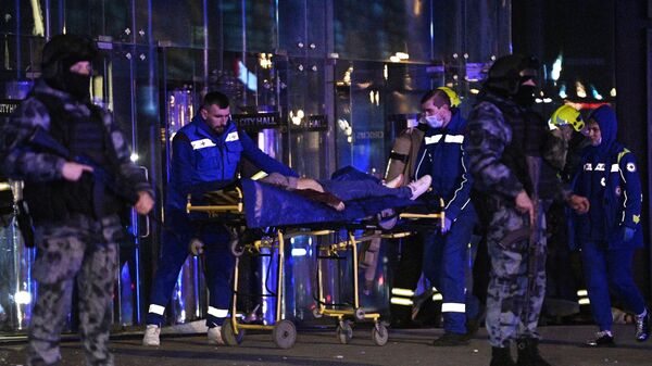 Сотрудники скорой помощи вывозят раненых из концертного зала Крокус Сити Холл, где произошла стрельба