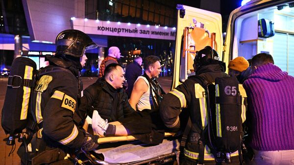 Сотрудники скорой помощи оказывают помощь пострадавшей у концертного зала Крокус Сити Холл в Москве, где произошла стрельба. 22 марта 2024