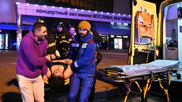 Сотрудники скорой помощи оказывают помощь пострадавшей у концертного зала Крокус Сити Холл в Москве