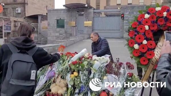 Жители Армении несут венки, цветы и мягкие игрушки к зданию посольства России в Ереване в память о погибших в теракте в Подмосковье