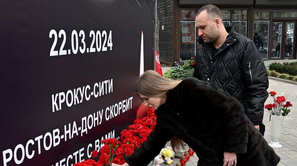 Люди возлагают цветы к стихийному мемориалу в память о жертвах теракта в подмосковном Крокус Сити Холле