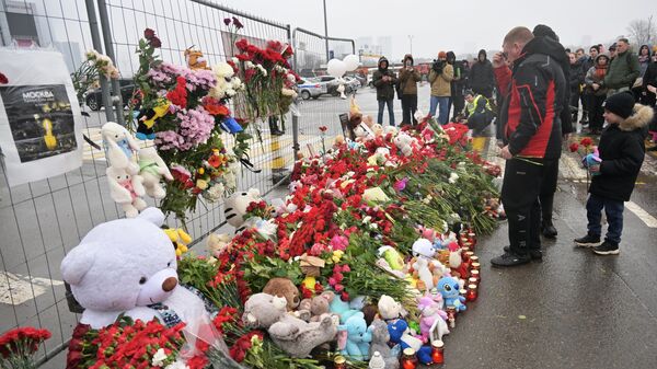 Цветы, игрушки и свечи на стихийном мемориале возле подмосковного Крокус Сити Холла в память о жертвах теракта