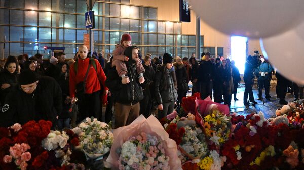 Люди у стихийного мемориала возле подмосковного Крокус Сити Холла в память о жертвах теракта