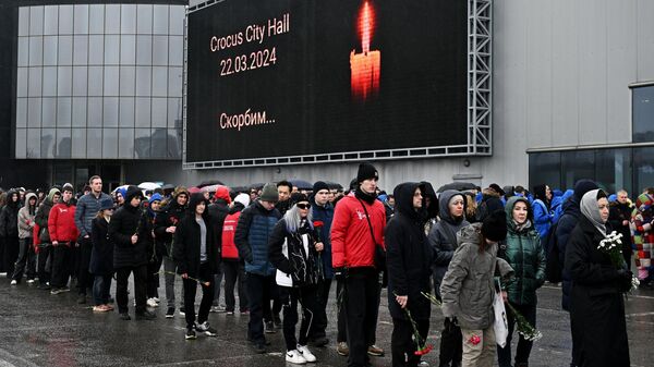 Люди стоят в очереди к стихийному мемориалу возле подмосковного Крокус Сити Холла в память о жертвах теракта